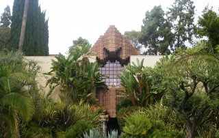 The historic Sowden House in Los Feliz surrounded by trees and tropical plants.
