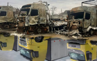 Burned trucks parked beside a puddle near the Good Wine warehouse.